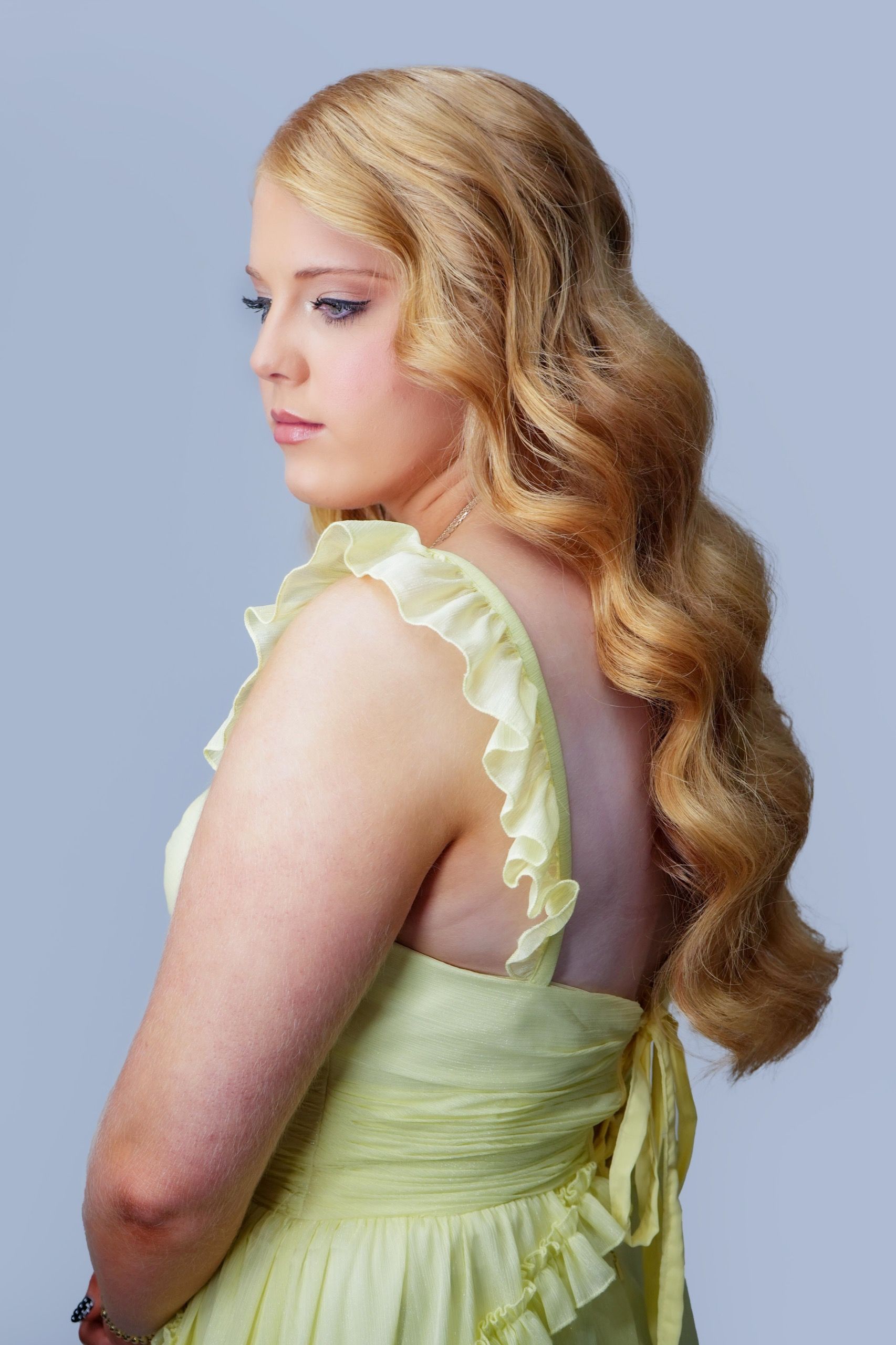 Bride with redhead hair styled in glam waves, wearing yellow dress, soft wedding makeup with neutral tones and long lashes.