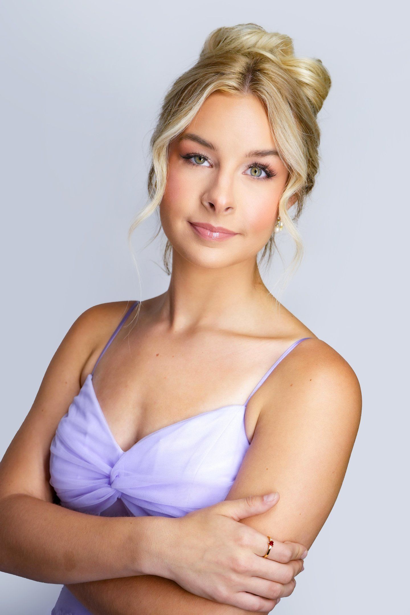 Bride with blonde hair in elegant updo, soft glam wedding makeup, glowing skin, long lashes, and natural pink lipstick.